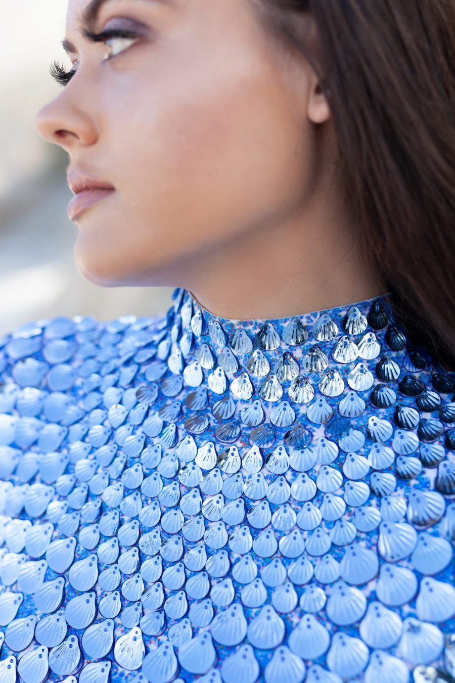 A shimmering aqua blue festival dress covered in shell-shaped sequins, designed with a mermaid-inspired silhouette and built-in bodysuit for comfort. The dress catches the light with every movement, creating a sea breeze effect, perfect for festivals or evening events.